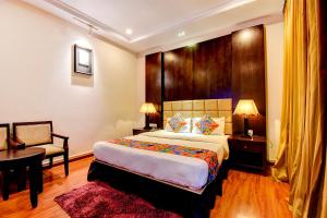 a bedroom with a bed and a table and a chair at FabHotel Suvee Boutique Banashankari in Bangalore