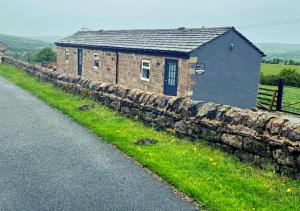 a building on the side of a stone wall next to a road at Chevin End Guest House in Otley