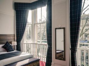 a bedroom with a bed and a mirror and a window at Argyll Western Hotel in Glasgow