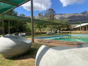 a swimming pool with chairs and a house at Tulbagh Mountain Cabin in Wolseley