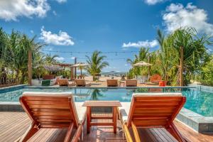 a pool at the resort with chairs and a table at Pousada de Charme Villa Italiana - Pé na Areia in São Miguel dos Milagres