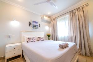 a bedroom with a large white bed and a window at Shakespeare Court Serviced Apartments in Lusaka