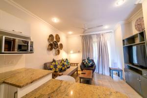a living room with a kitchen and a living room with a couch at Shakespeare Court Serviced Apartments in Lusaka