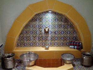 a kitchen with a tile wall with two buckets at Dar Baaziz in Sousse