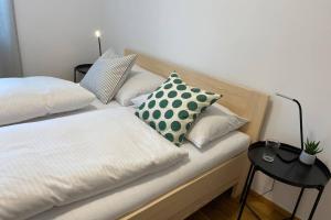 een bed met twee kussens en een bijzettafel bij Wohnung 2 in zentraler Lage im Rheintal in Götzis