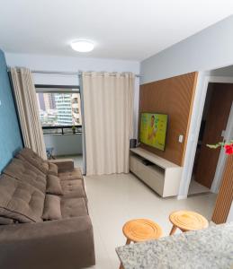 a living room with a couch and a tv at Apartamento Auto padrão 2 quartos vista mar praia da armação in Salvador