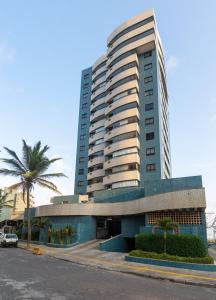a tall building with a palm tree in front of it at Apartamento Auto padrão 2 quartos vista mar praia da armação in Salvador