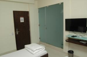 a room with a room with a tv and a stool at Hotel Causeway, Colaba in Mumbai