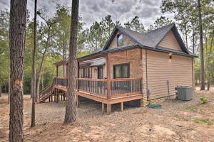 eine Hütte im Wald mit einer großen Terrasse in der Unterkunft Modern Cabin with Spacious Deck, BBQ, and Pergola! in Broken Bow