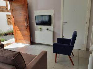 a living room with a tv and a couch and a chair at Las Gardenias in Florianópolis