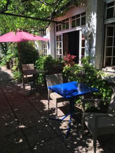 une table bleue, des chaises et un parasol rose dans l'établissement La Roseraie Biebler, à Jungholtz