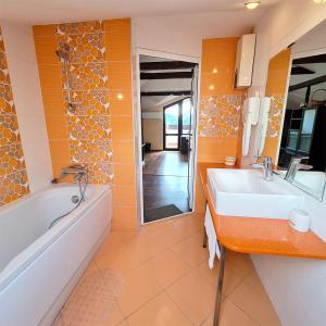 ein Badezimmer mit einer Badewanne und einem weißen Waschbecken in der Unterkunft Family Hotel Chiflik Hills in Chiflik