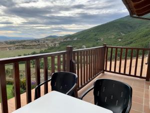 a balcony with two chairs and a table and mountains at Badaguás (Jaca) - Duplex en el Pirineo in Jaca