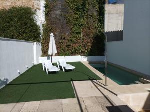 a patio with two lawn chairs and an umbrella at Casa Rural Alcalde Rivera in La Carrasca