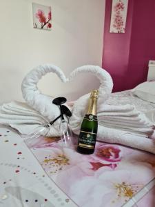 Una botella de champán sentada en una cama con corazones en Studio Le Pavachon 2 à 3 couchages, piscine familiale chauffée, 3 min du Puy du Fou Les Epesses, en Les Épesses