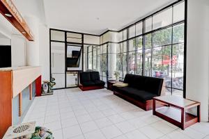 uma sala de estar com dois sofás pretos e janelas em Super OYO Flagship 90658 Hotel Asteria em Bandung