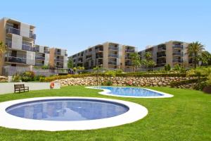 a pool in the middle of a lawn with apartment buildings at Rentalmar Paradise Families Only con parking in Salou