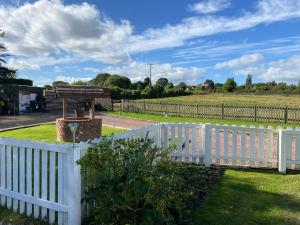a white picket fence with a grill in a field at fairfeilds cottage Frog Trotters Bottom in Hartpury