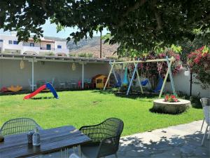 un patio con mesa de picnic y parque infantil en Allegria Family Hotel, en Agios Petros