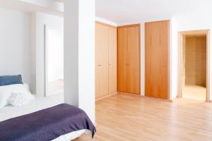 a bedroom with white walls and a bed and wooden cabinets at Fira Duplex in Hospitalet de Llobregat