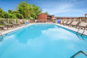 uma grande piscina azul com cadeiras e uma cerca em Super 8 by Wyndham Sandusky em Sandusky