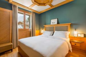 a bedroom with a large bed and a window at Radisson Residences Savoia Palace Cortina d’Ampezzo in Cortina dʼAmpezzo
