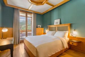 a bedroom with a large bed and a large window at Radisson Residences Savoia Palace Cortina d’Ampezzo in Cortina dʼAmpezzo