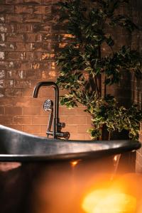 a bath tub with a faucet in front of a brick wall at South Causey Inn in Stanley