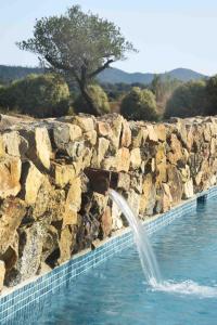 una fuente en una pared de piedra junto a una piscina en Mas Rauric, en Llagostera