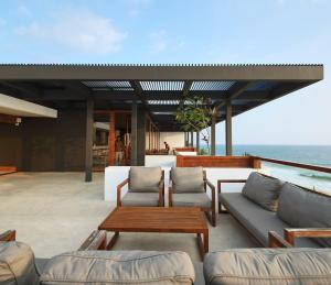 a patio with couches and tables and the ocean at Riff Hikkaduwa in Hikkaduwa