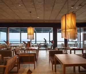 a restaurant with wooden tables and chairs and windows at Riff Hikkaduwa in Hikkaduwa