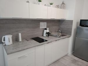 a white kitchen with a sink and a refrigerator at Apartament Oskar in Kołobrzeg