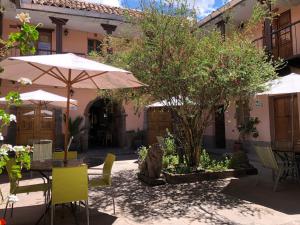 Un patio al aire libre con mesas, sillas y sombrillas. en Hostal Qorichaska, en Cusco