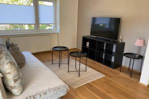 ein Wohnzimmer mit einem Sofa, 2 Tischen und einem TV in der Unterkunft Terrassenwohnung in Götzis in Götzis