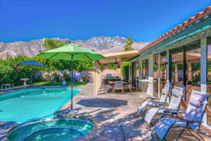 une maison dotée d'une piscine avec des chaises et un parasol dans l'établissement My Palm Springs Place Permit# 3042, à Palm Springs
