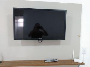 a television on a wall with a person taking a picture at Apart Plaza Fraga Maia in Feira de Santana