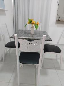 a table and chairs with a vase of flowers on it at Apart Plaza Fraga Maia in Feira de Santana +3 photos