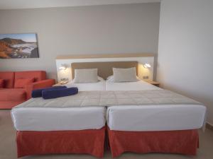 a bedroom with a large bed and a red couch at Hotel Lanzarote Village in Puerto del Carmen