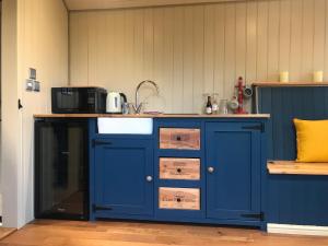 a kitchen with a blue cabinet and a microwave at Highkettle Hut in Chichester