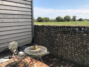 einen Tisch und einen Stuhl auf einer Terrasse neben einer Wand in der Unterkunft Highkettle Hut in Chichester