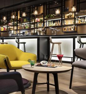 a bar with yellow chairs and a table with a drink at INNSiDE by Meliá Paris Charles de Gaulle Airport in Roissy-en-France