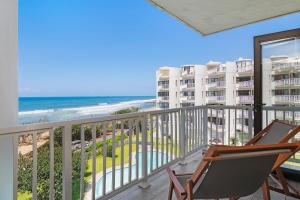 een balkon met 2 stoelen en uitzicht op het strand bij Escape to a Coastal Oasis in Umdloti