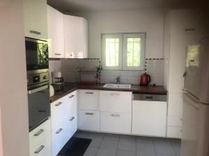 uma cozinha com armários brancos e um lavatório em Warblers View em Biot