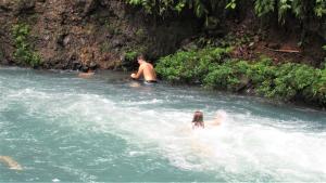 un gruppo di persone che nuotano in un fiume di Cabinas Río Celeste La Amistad a Rio Celeste