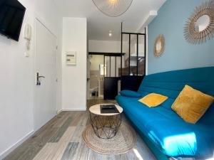 ein Wohnzimmer mit einem blauen Sofa und einem Tisch in der Unterkunft Studios Sauzède - Carcassonne centre-ville in Carcassonne