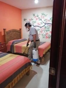 a man vacuum cleaning a bedroom with two beds at Hotel Amayal in San Cristóbal de Las Casas