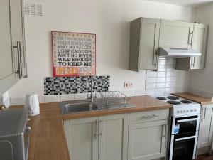 a kitchen with white cabinets and a sink at Golden Triangle House in Norwich