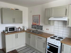 a kitchen with white cabinets and a stove top oven at Golden Triangle House in Norwich