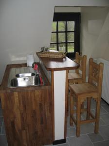 a kitchen with a sink and a counter with two chairs at Le Champ des Possibles in Manerbe