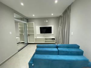 salon z niebieską kanapą i telewizorem w obiekcie Waikiki Apartament Ipanema w mieście Rio de Janeiro